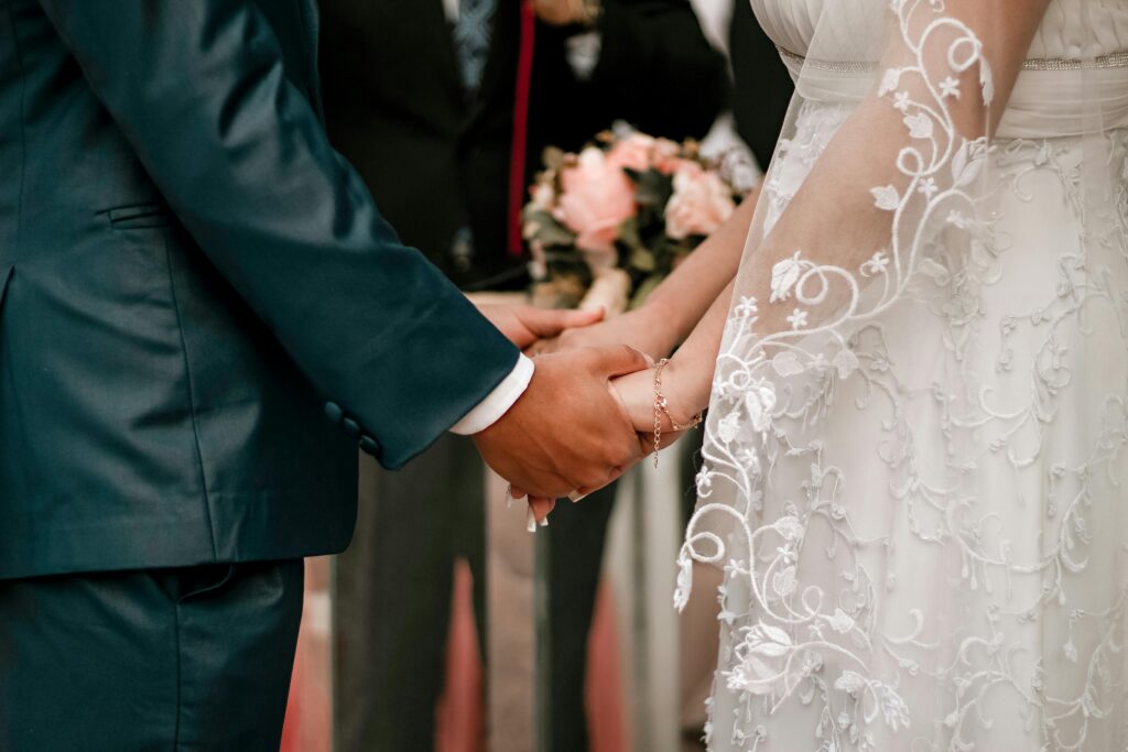 A couple holding hands during their wedding ceremony, symbolizing love and commitment.
